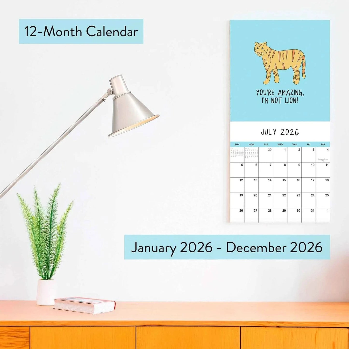The 2026 Wall Calendar "You've Got To Be Yolking" by rockdoodles sits open on your desk, adding quirky charm alongside your lamp, plant, and books—the perfect fun calendar for any workspace.
