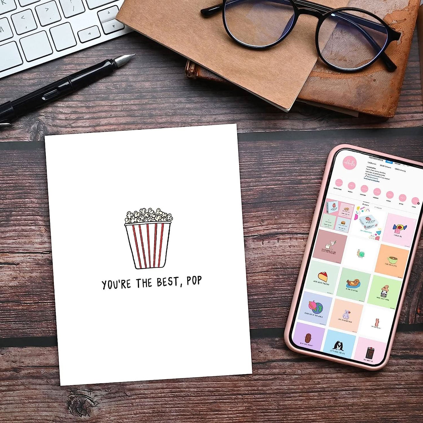 The rockdoodles Best Pop Card accompanied by a phone and a bowl of popcorn for the perfect movie night.