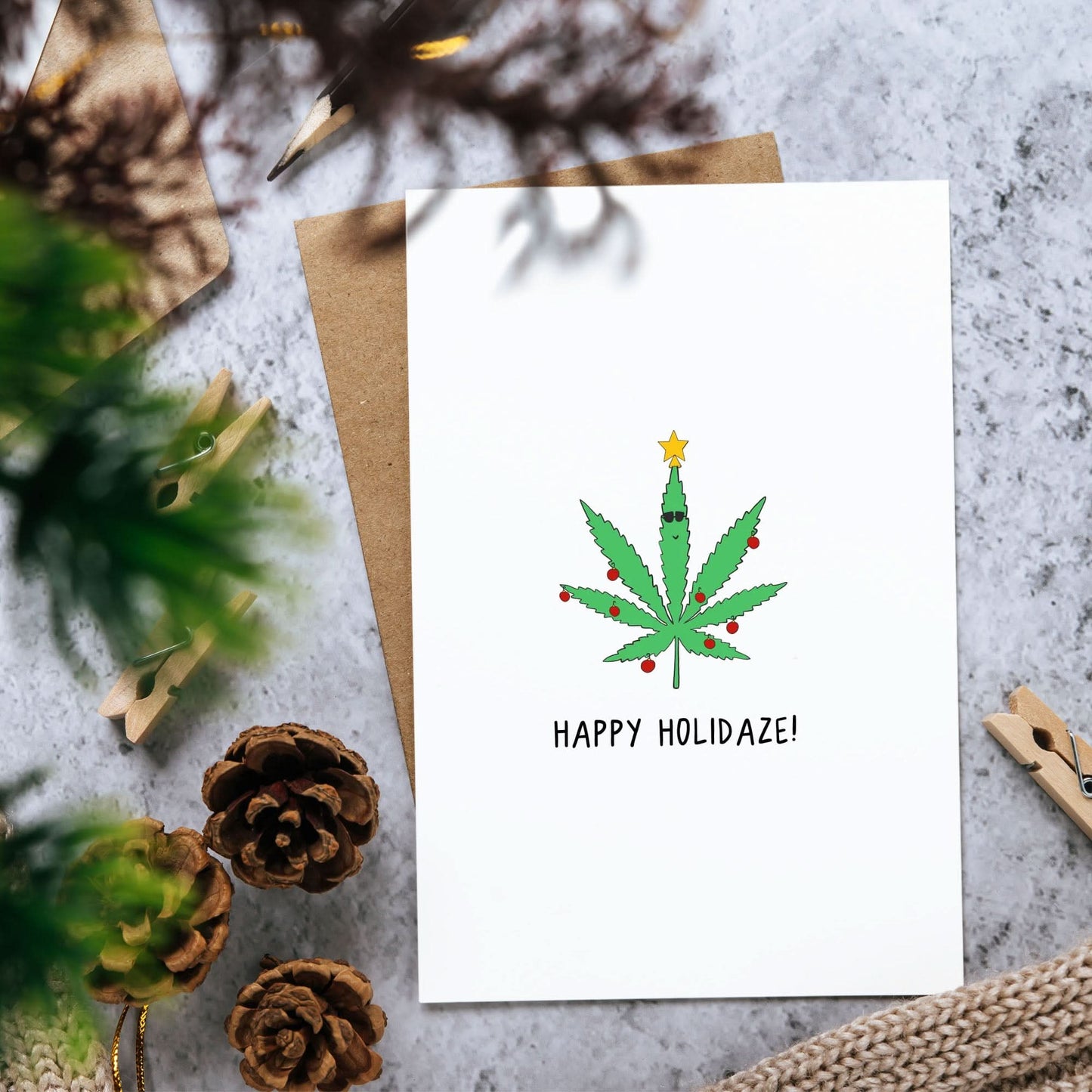 A rockdoodles Holidaze card with a marijuana leaf on it, enclosed in a natural envelope.