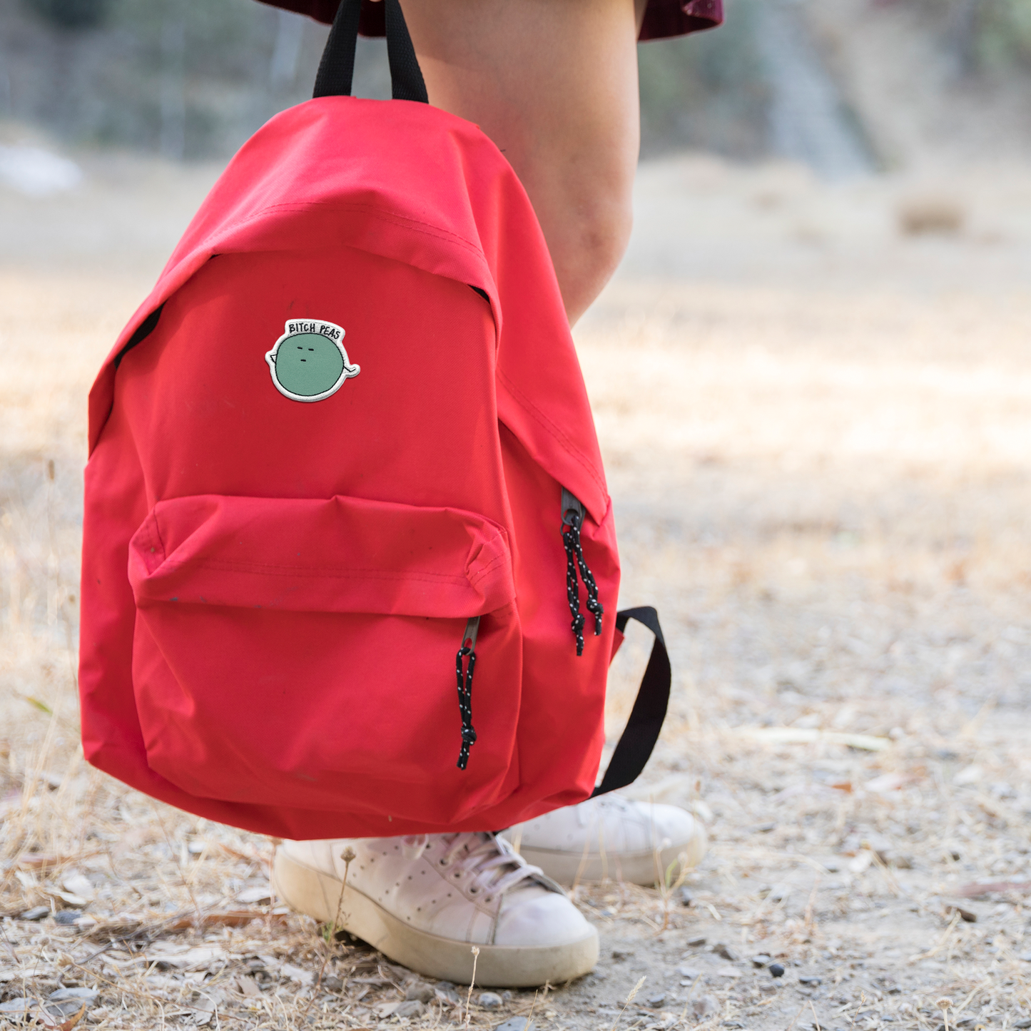 A girl wearing a backpack with a B**** Peas Patch by rockdoodles on it.