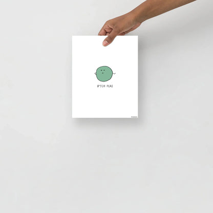 A person holding up a framed B**** Peas Print with a green circle on matte paper, made by rockdoodles.