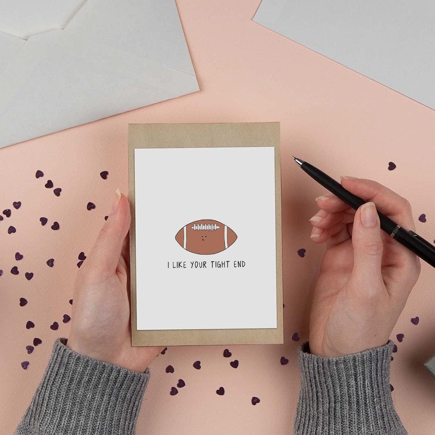 In this image, a person is seen holding a rockdoodles I Like Your Tight End Card and envelopes tightly.