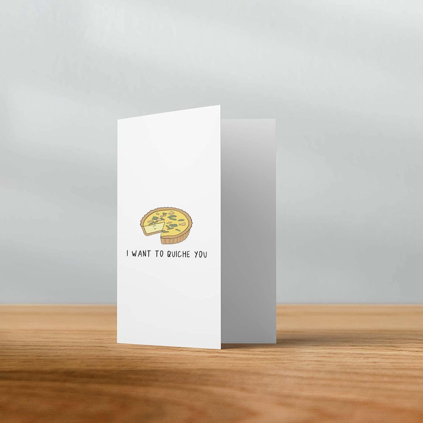 A rockdoodles greeting card with an image of an I Want To Quiche You Card on it, enclosed in an envelope.