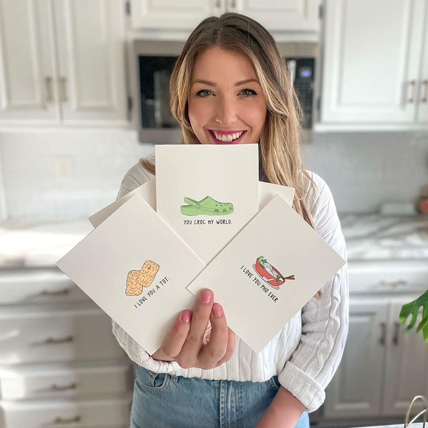 A woman tightly holding up a group of rockdoodles I Like Your Tight End cards.