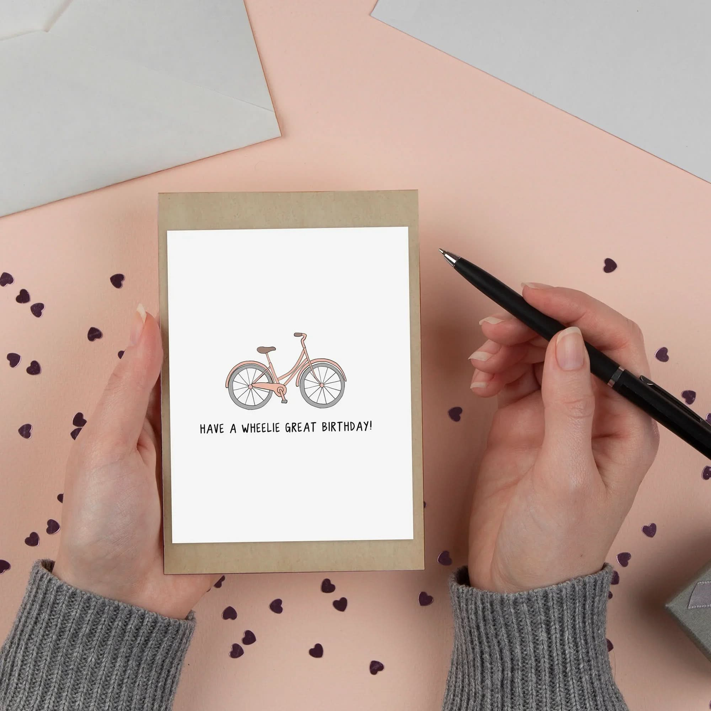 A person writing a rockdoodles Wheelie Great Birthday Card message on a card measuring 4.25 in. x 5.5 in.