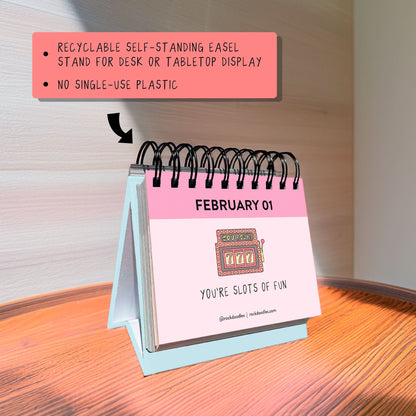 The rockdoodles "A Pun A Day Perpetual Calendar" is a small spiral-bound desk calendar, shown on a wooden surface with February 1 featuring a slot machine and the pun "YOU'RE SLOTS OF FUN”—a fun gift for pun lovers.