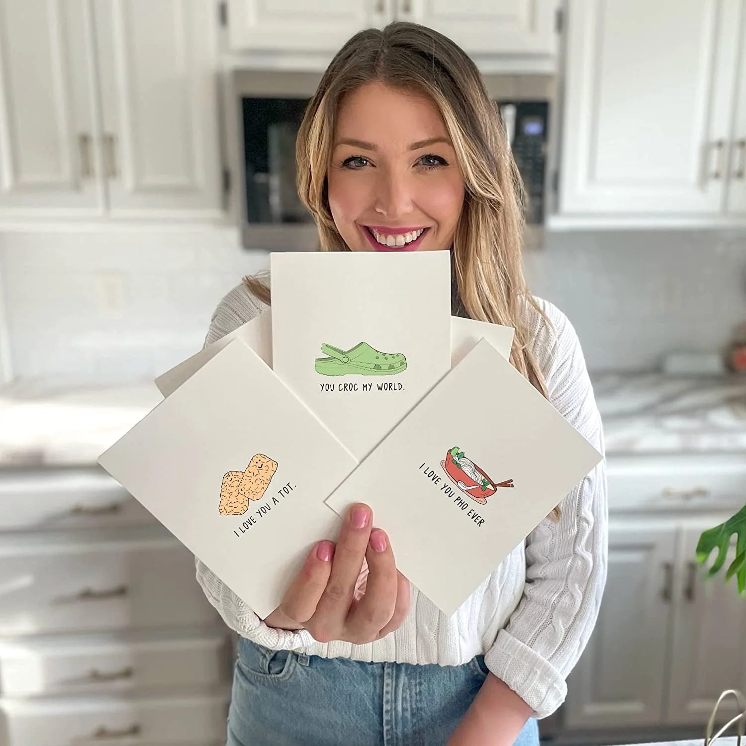 A woman holding up a Holidaze Card with a crocodile on it from rockdoodles.