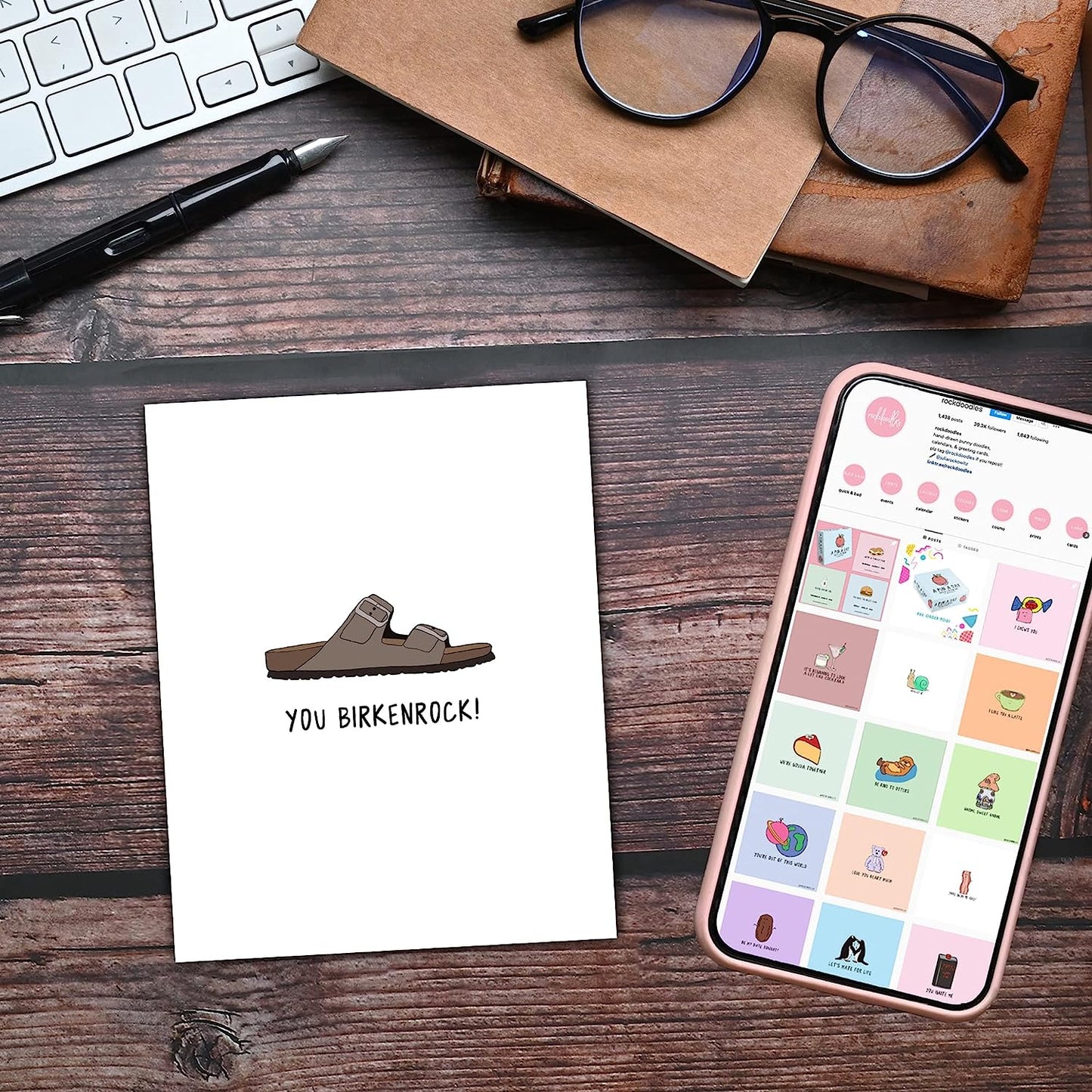 A rockdoodles Age Is Irrelephant card with the words you're welcome on it placed next to a phone and glasses.