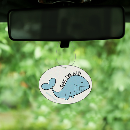 A Seas The Day (2-Pack) Punny Air Freshener - Ocean Scent hangs from the rearview mirror of a car.