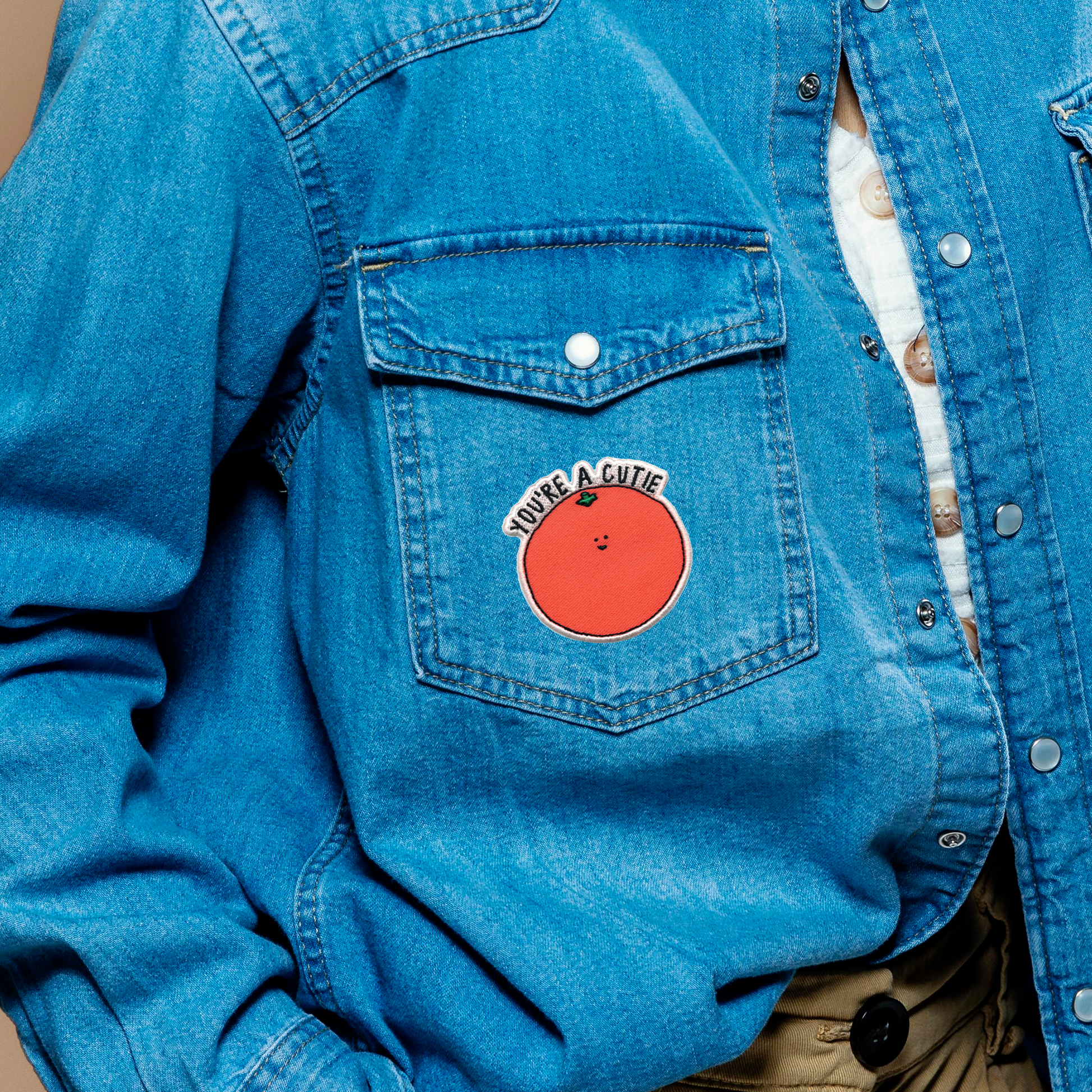 A woman wearing a denim jacket with a rockdoodles iron-on You're A Cutie Patch.