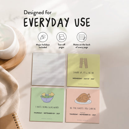 Four illustrated daily pages from the rockdoodles 2027 A Pun A Day Desktop Calendar, each featuring humorous, pun-filled drawings and food-themed quotes, are arranged on a beige surface next to a white cup and plate. Text highlights features such as holidays, tear-off pages, space for notes, and emphasizes that this plastic-free 2027 daily calendar is designed to keep you smiling all year.