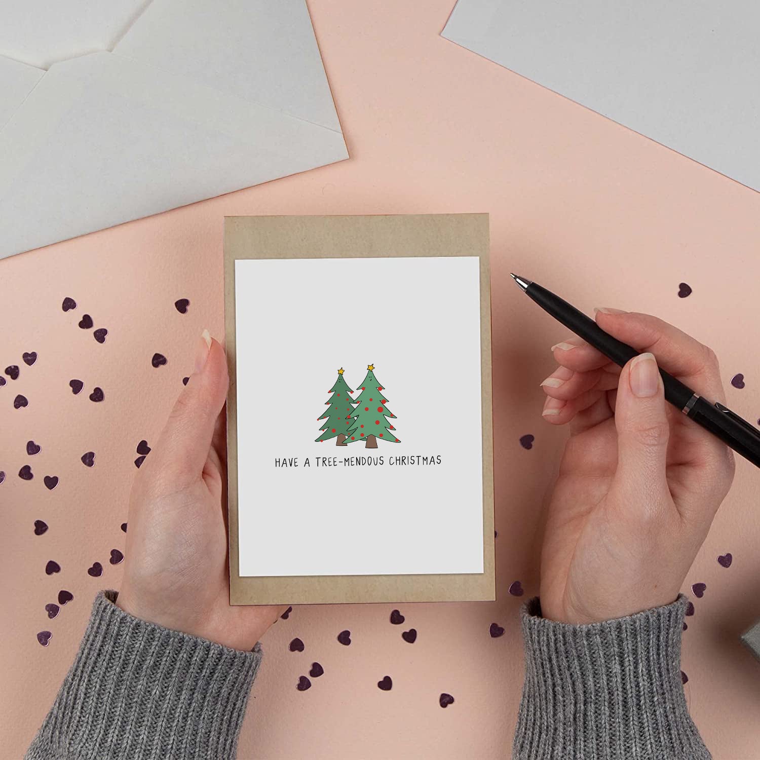 A person holding a rockdoodles Have A Tree-Mendous Christmas Card with a blank inside and a Christmas tree on it.