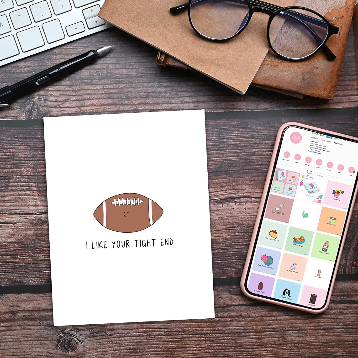 A notebook with a I Like Your Tight End Card by rockdoodles on it, and a cell phone encased in an envelope.