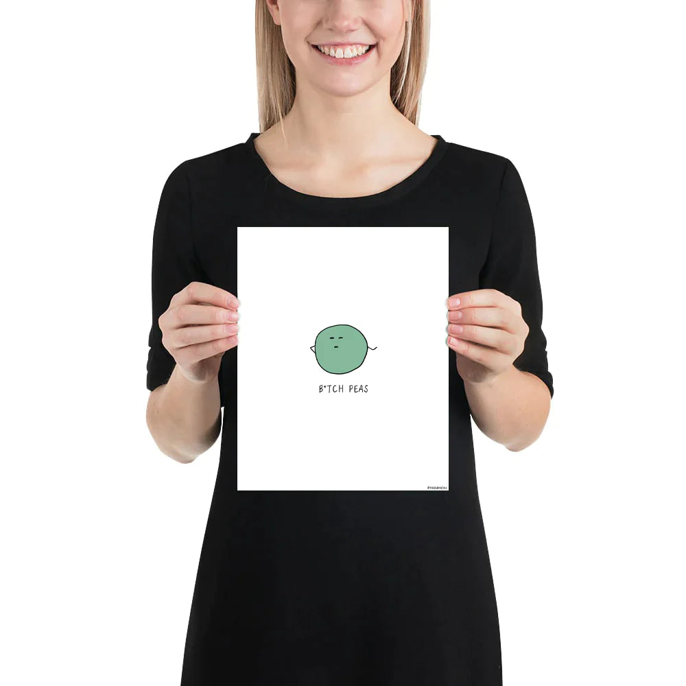 A woman proudly displaying a framed B**** Peas Print by rockdoodles with the humorous phrase "I'm a worm" on matte paper.