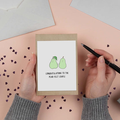 A woman holding a rockdoodles Pear-Fect Couple Card, congratulating someone.