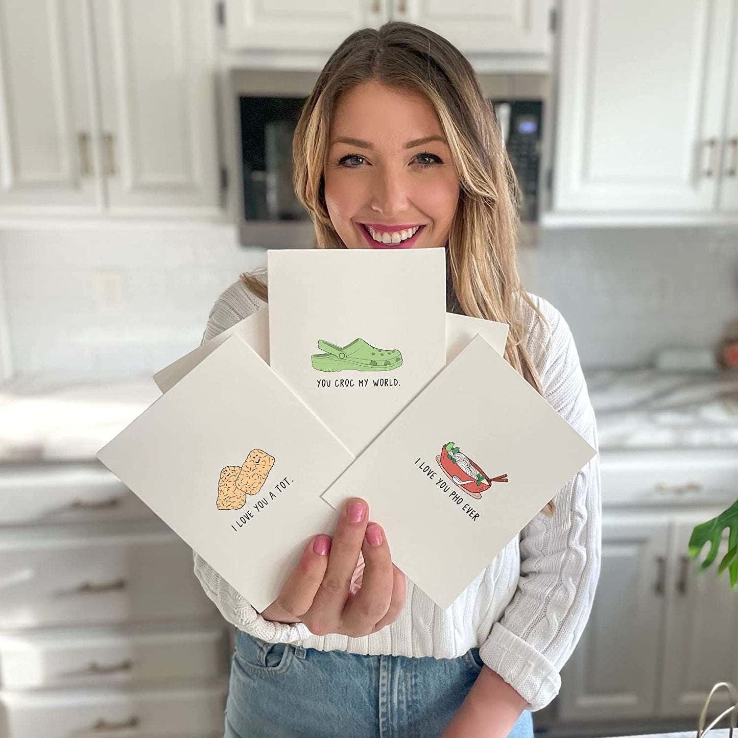 A woman holding up a set of rockdoodles card envelopes with a crocodile on them.